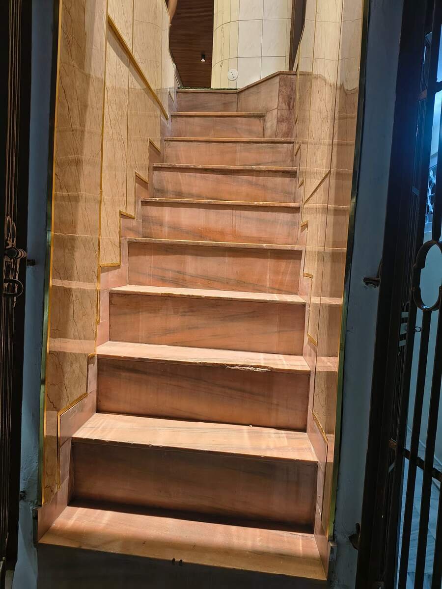Pink stone staircase with brass inlay leading up from the street